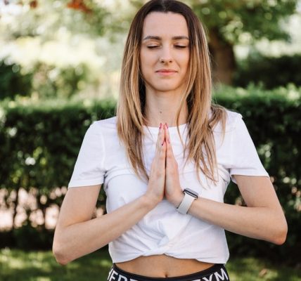 A serene moment of a woman practicing yoga with namaste pose outdoors, embracing mindfulness.