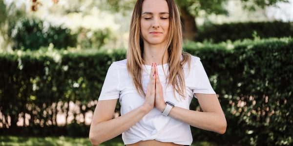 A serene moment of a woman practicing yoga with namaste pose outdoors, embracing mindfulness.